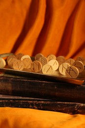 Wooden runes and old books on orange fabric
