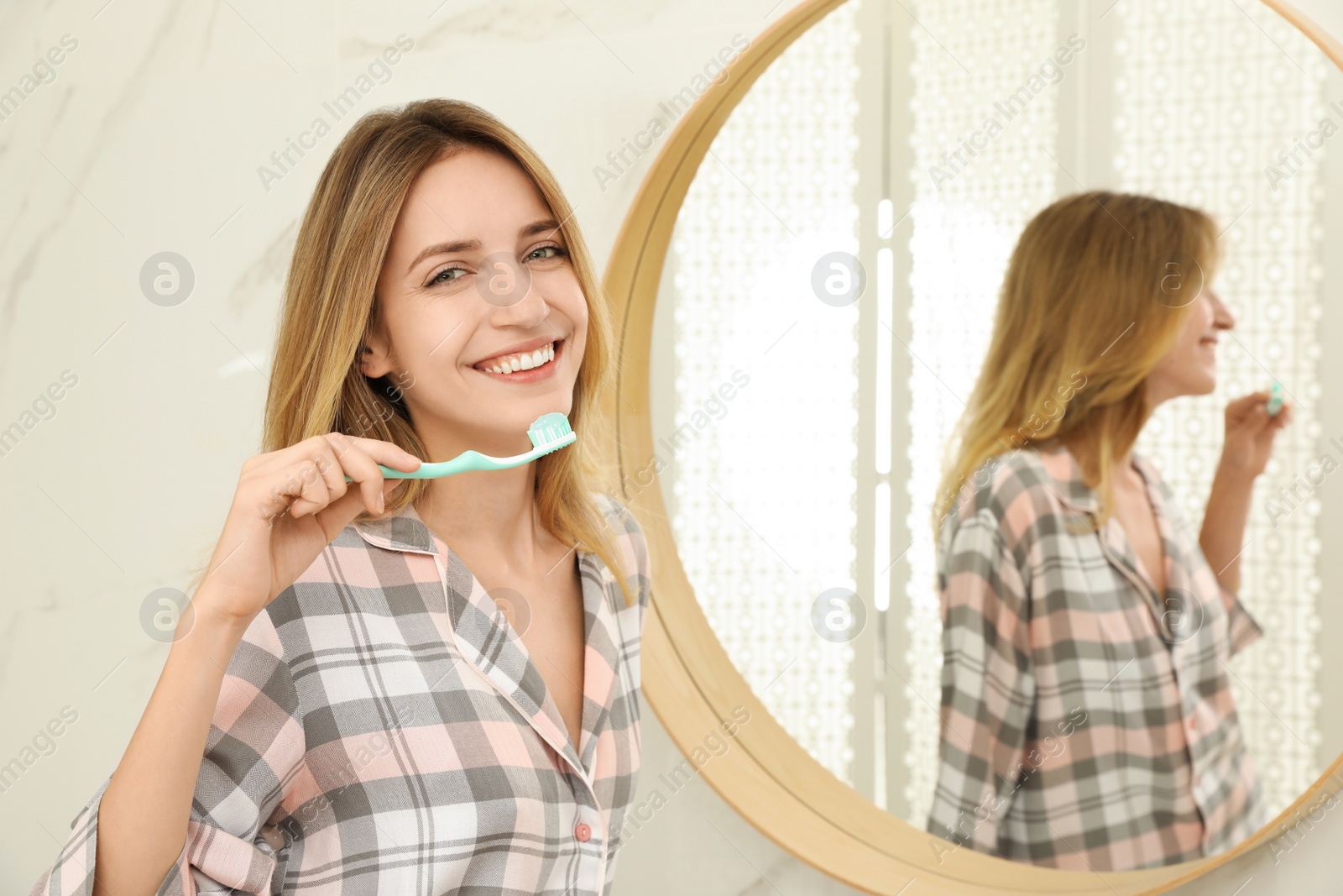 Photo of Woman brushing teeth near mirror in bathroom