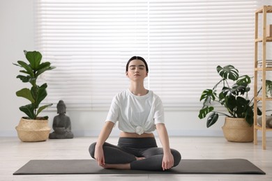 Photo of Beautiful girl meditating on mat in yoga studio