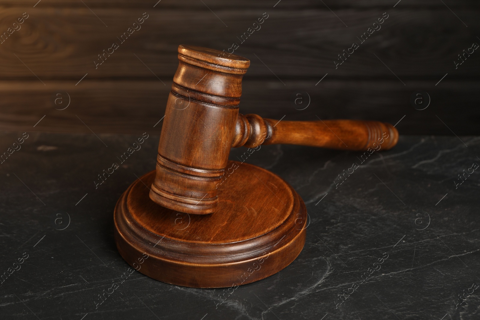 Photo of Wooden gavel on dark textured table, closeup