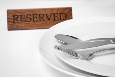 Elegant table setting and RESERVED sign in restaurant, closeup