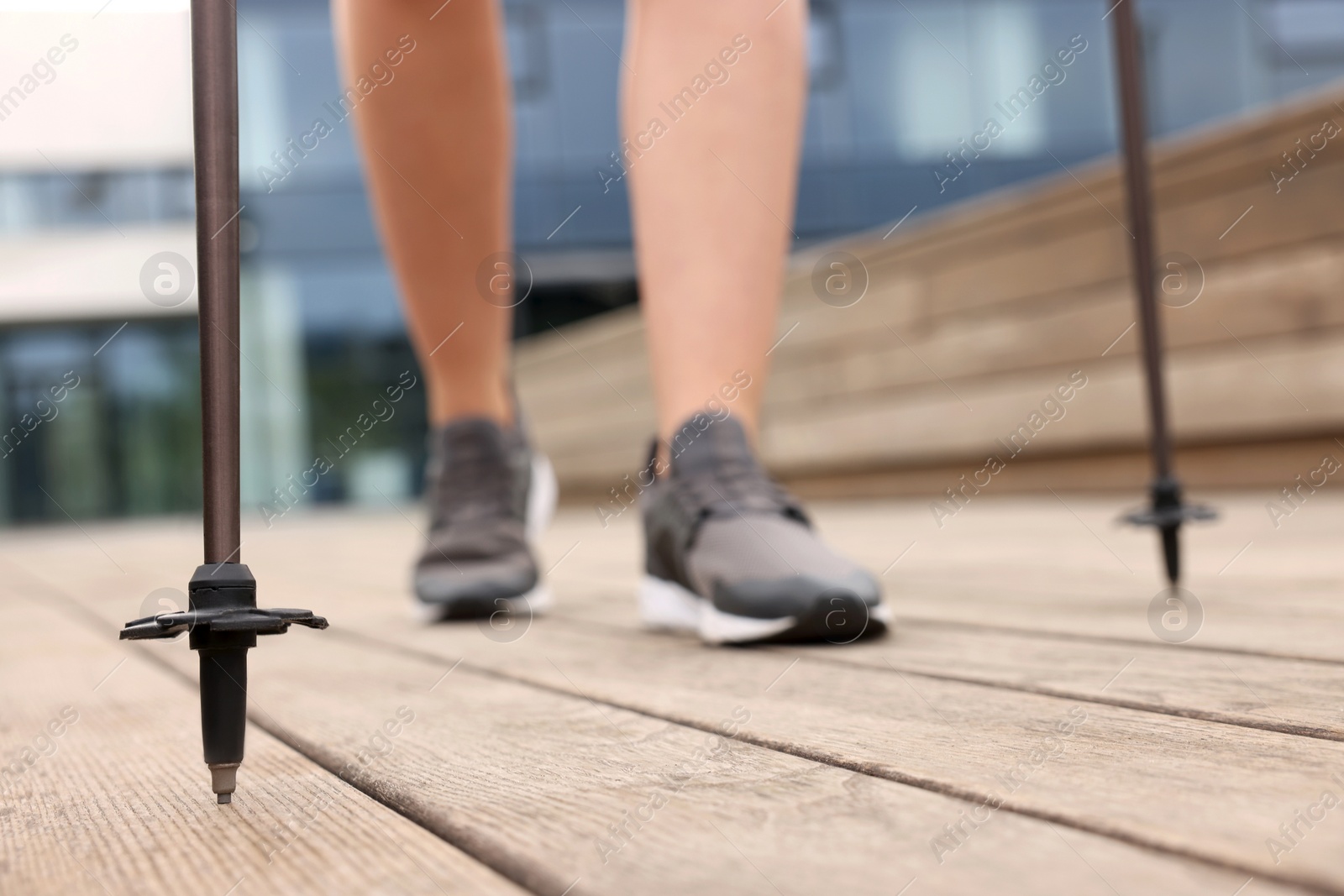 Photo of Young woman practicing Nordic walking with poles outdoors, selective focus