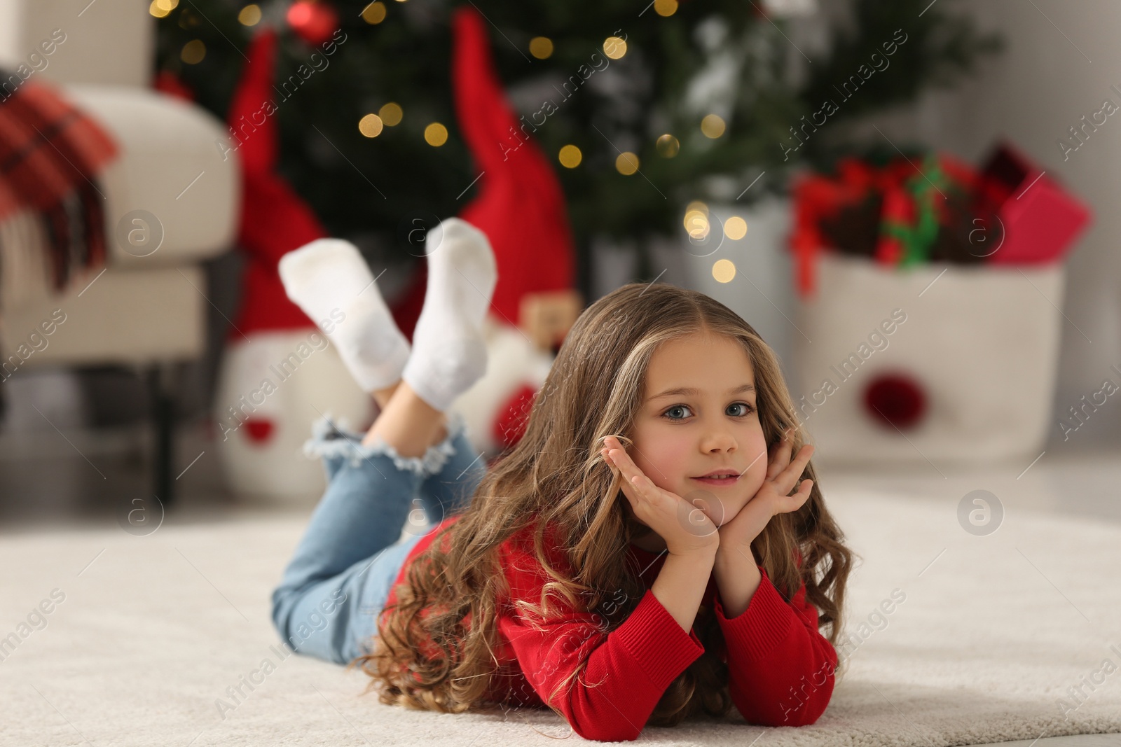 Photo of Little girl lying on soft carpet at home. Christmas atmosphere