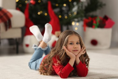 Little girl lying on soft carpet at home. Christmas atmosphere