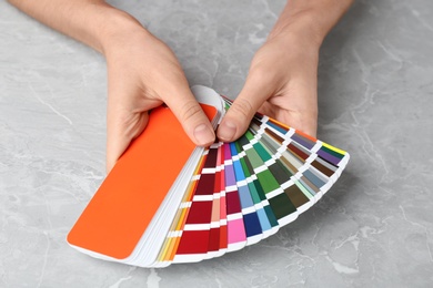 Photo of Woman with palette samples at grey marble table, closeup