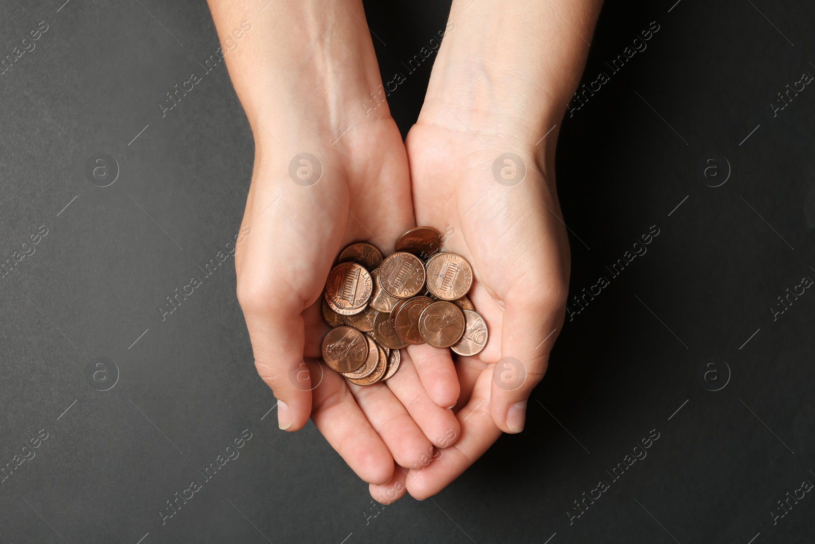 Photo of Young woman holding coins on black background, top view