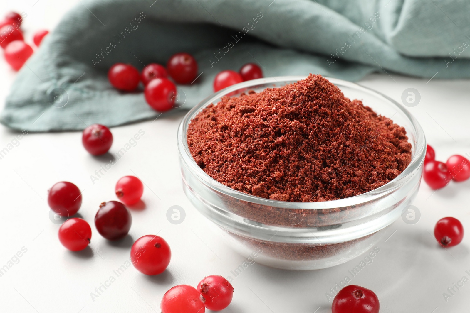 Photo of Dried cranberry powder in bowl and fresh berries on white table, closeup