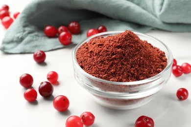 Dried cranberry powder in bowl and fresh berries on white table, closeup