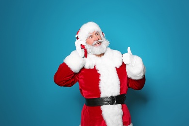 Santa Claus listening to Christmas music on color background