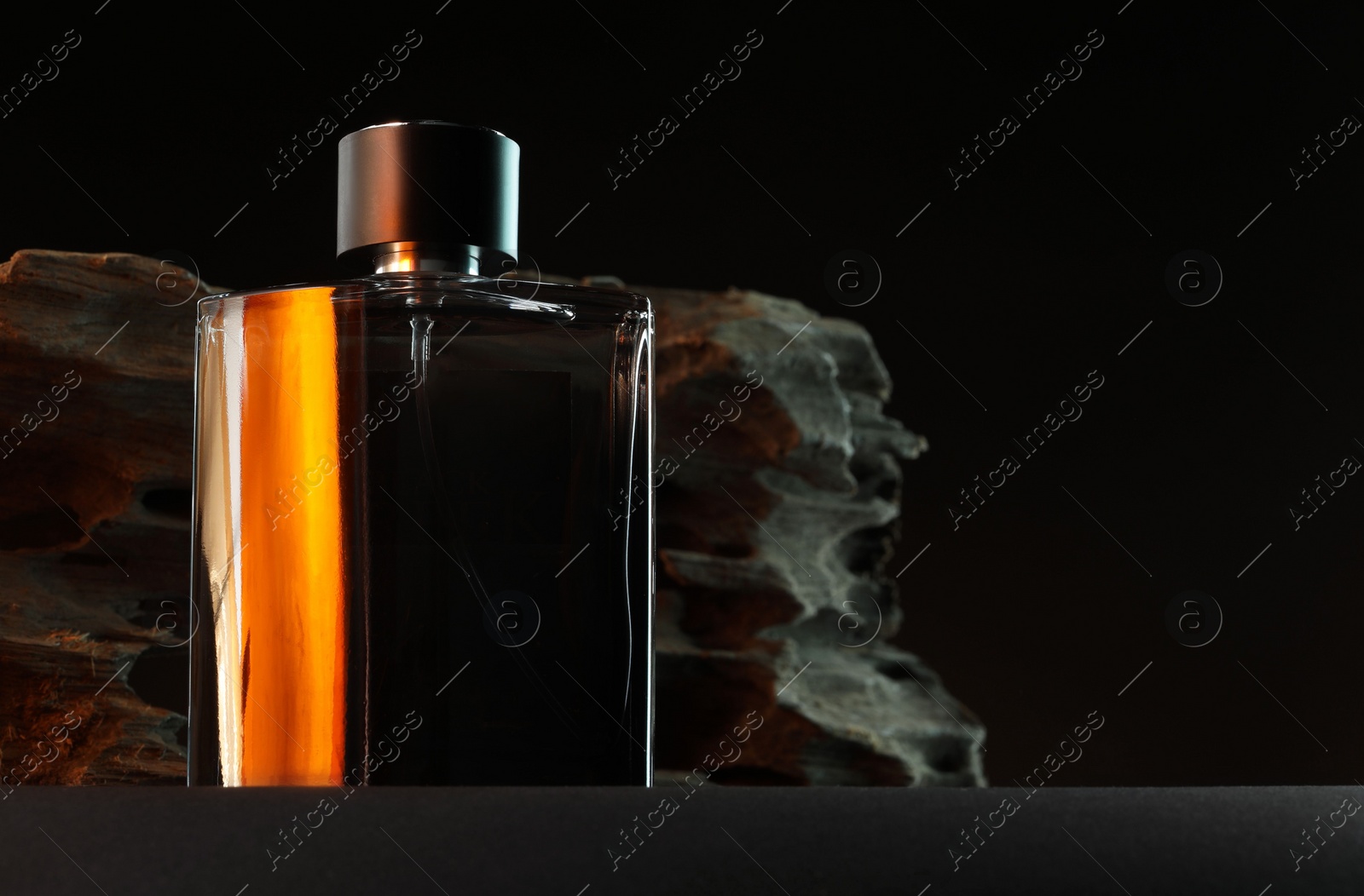 Photo of Luxury men`s perfume in bottle on grey table against dark background, space for text