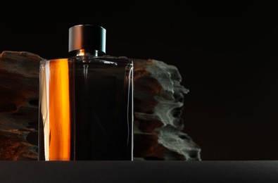 Luxury men`s perfume in bottle on grey table against dark background, space for text