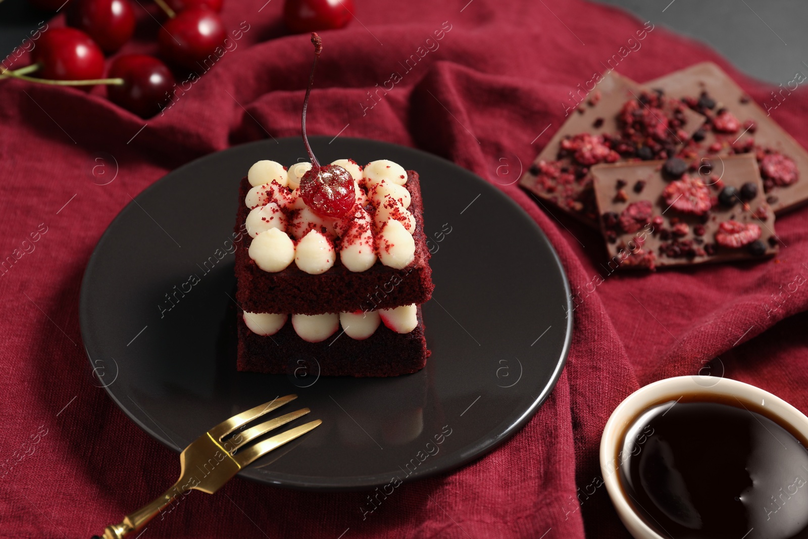 Photo of Piece of red velvet cake and fork on table, closeup