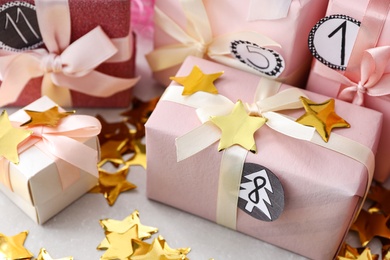 Photo of Gifts for Christmas advent calendar and confetti on light table, closeup