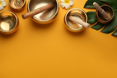 Photo of Flat lay composition with golden singing bowls on orange background. Space for text