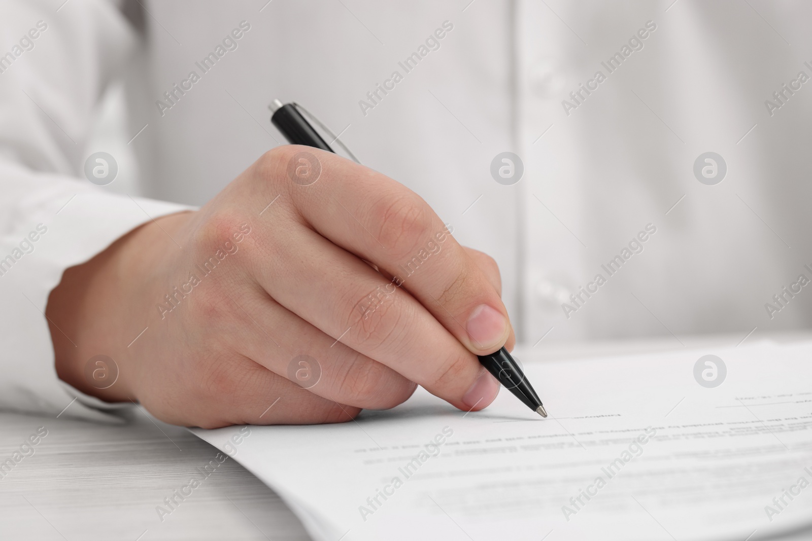 Photo of Man signing document at wooden table, closeup