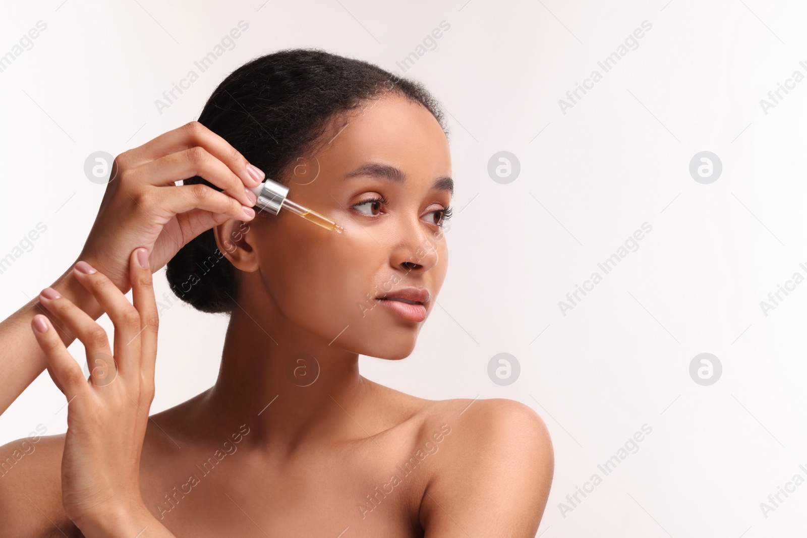 Photo of Beautiful woman applying serum onto her face on white background. Space for text