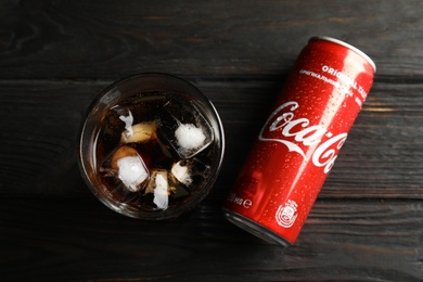 MYKOLAIV, UKRAINE - NOVEMBER 15, 2018: Glass and can with Coca Cola on wooden background, top view