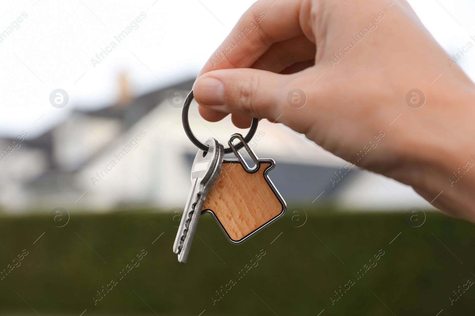 Photo of Woman holding house keys outdoors, closeup. Real estate agent