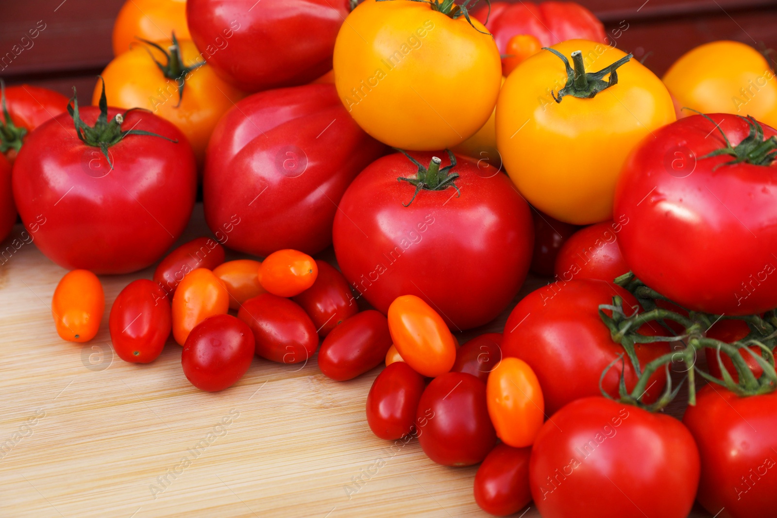 Photo of Different sorts of tomatoes on wooden table, space for text