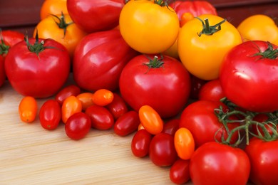 Different sorts of tomatoes on wooden table, space for text