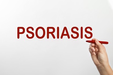 Image of Woman writing word PSORIASIS on white background, closeup