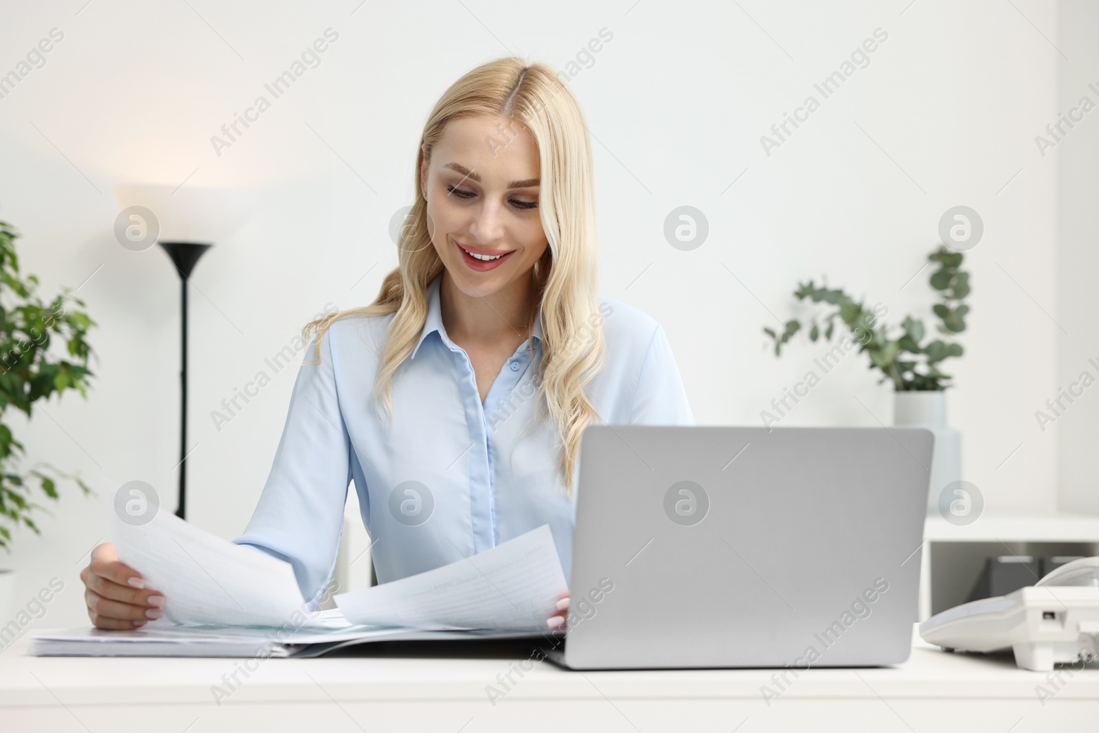 Photo of Happy secretary working with documents at table in office