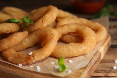 Photo of Delicious onion rings on wooden table, closeup