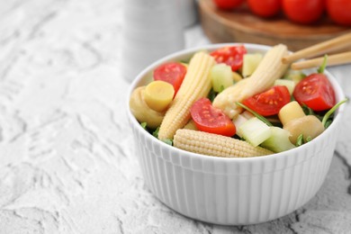 Tasty baby corn with vegetables and champignons on grey textured table, closeup. Space for text