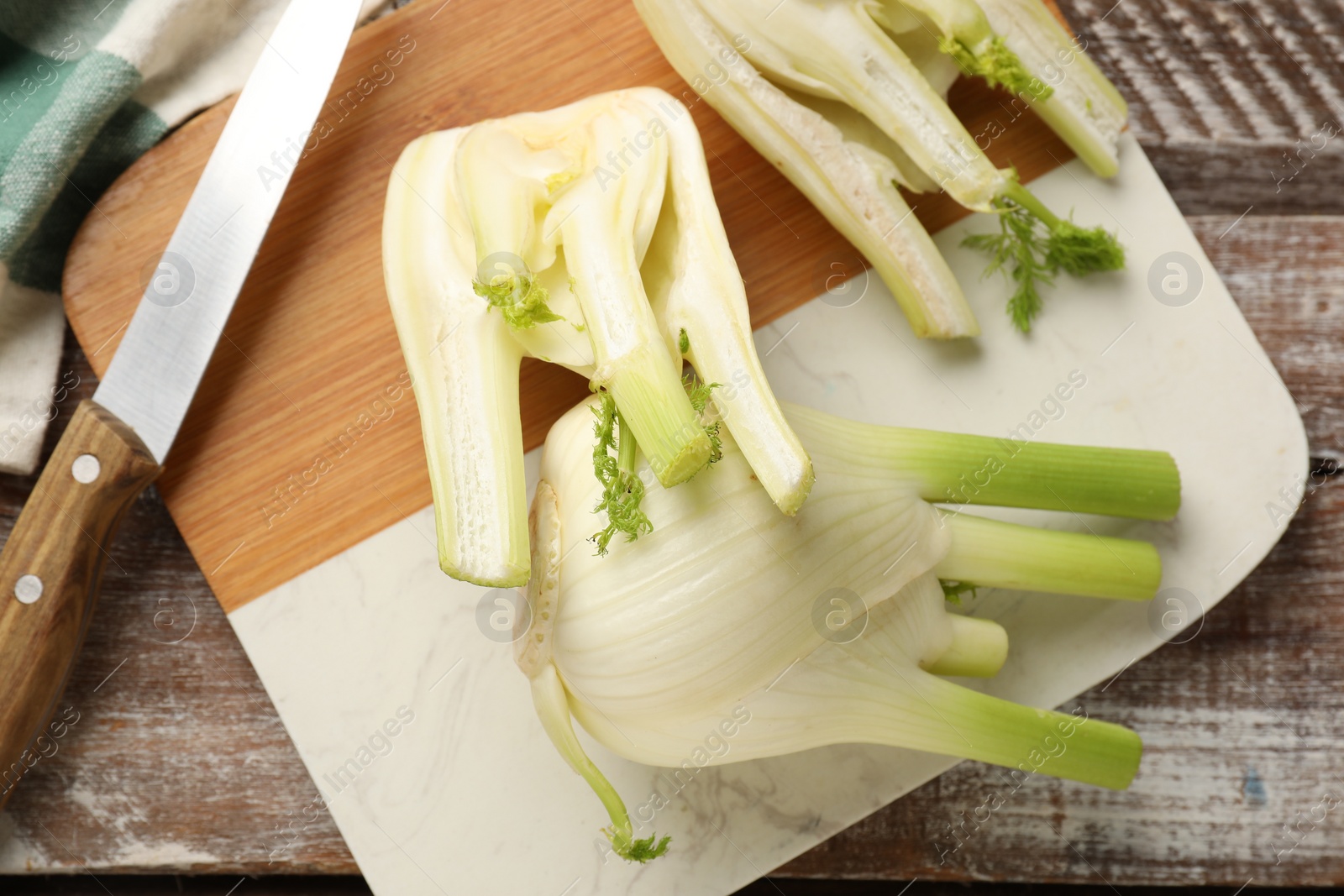 Photo of Fresh raw fennel bulbs and knife on wooden table, top view