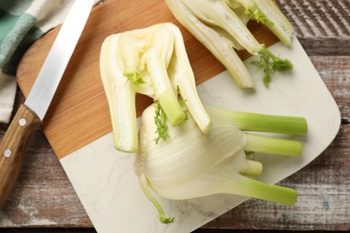 Fresh raw fennel bulbs and knife on wooden table, top view