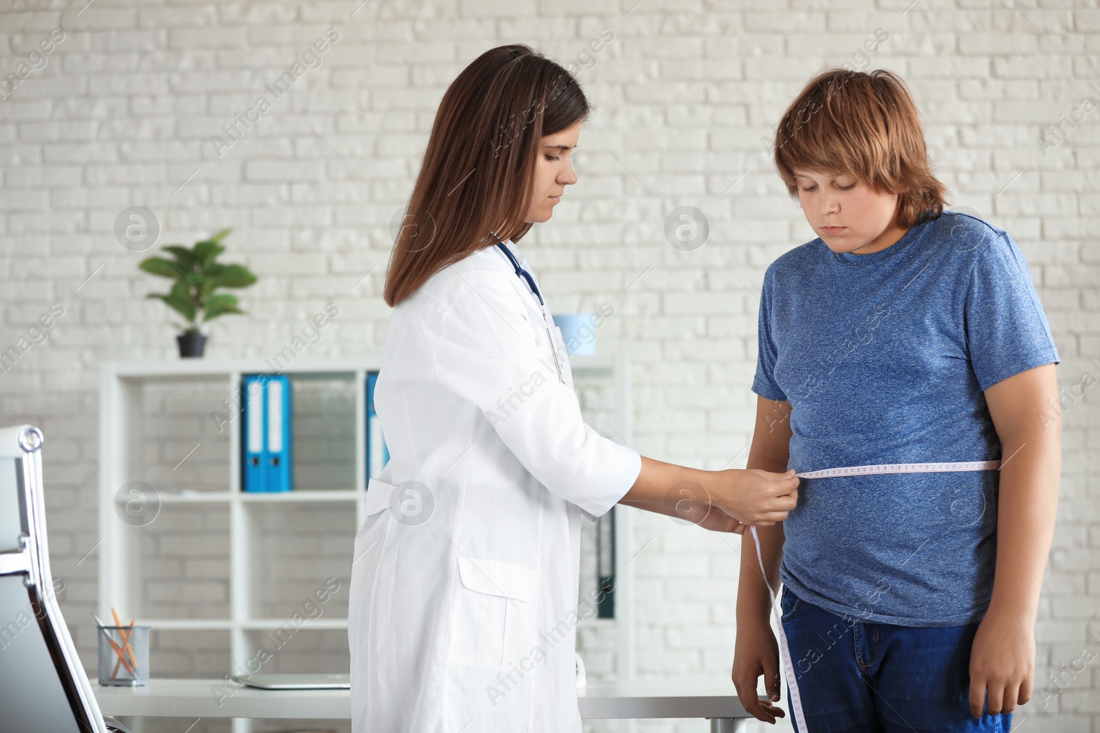 Photo of Female doctor measuring overweight boy in clinic