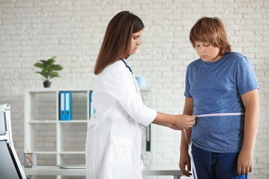 Female doctor measuring overweight boy in clinic