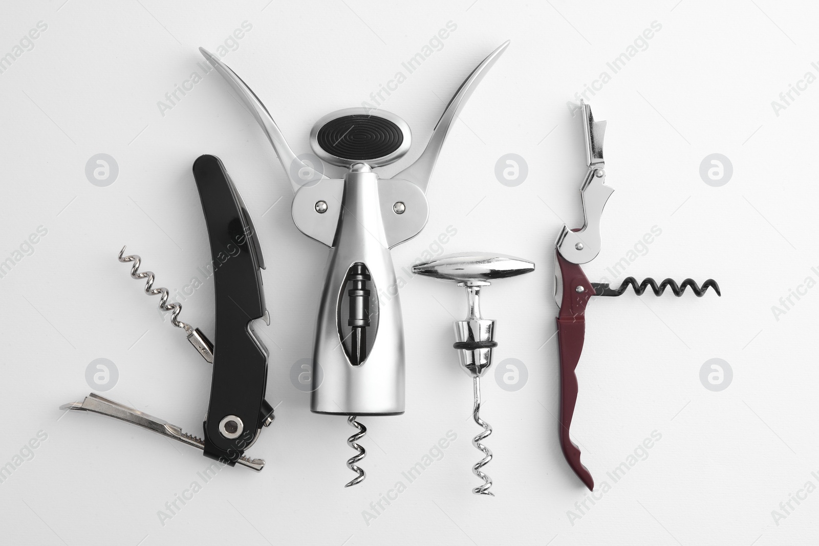 Photo of Different corkscrews on white background, flat lay