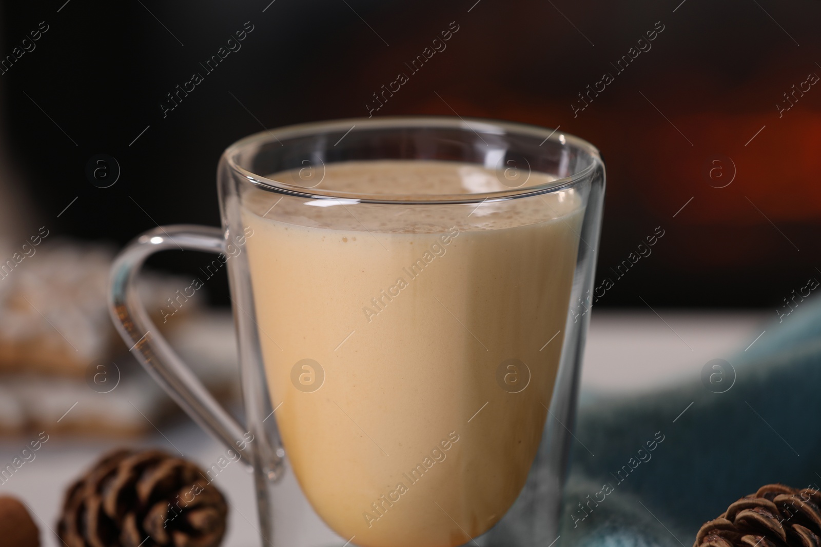 Photo of Tasty eggnog and cones on white table, closeup