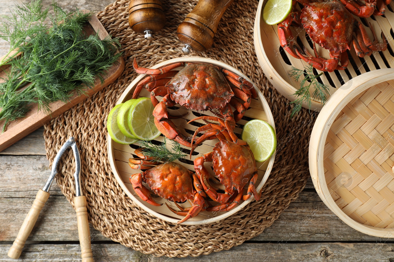 Photo of Delicious boiled crabs with lime on wooden table, flat lay