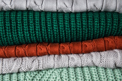 Photo of Heap of warm knitted clothes as background, closeup. Cozy autumn