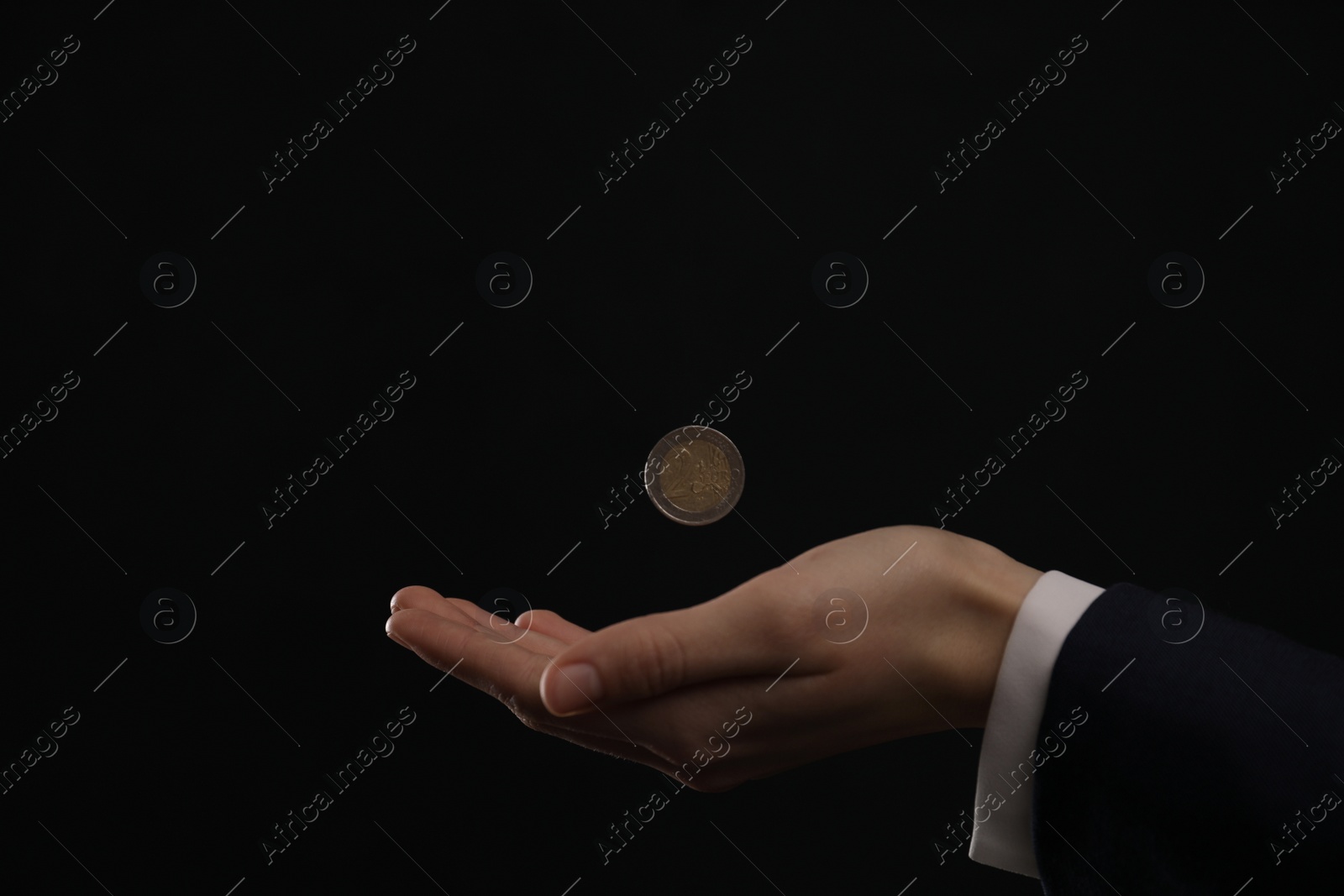 Photo of Businessman throwing coin on black background, closeup