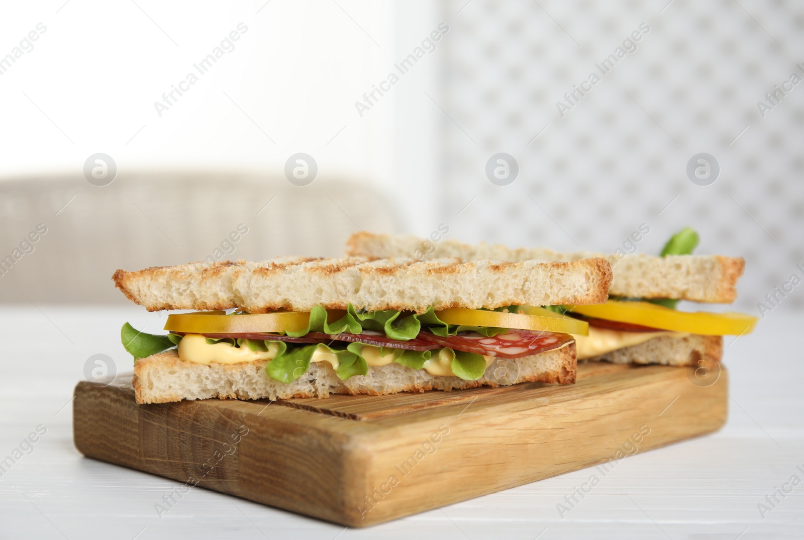 Photo of Wooden board with tasty sandwiches on white table. Space for text