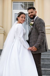 Photo of Young bride and groom on stairs outdoors. Wedding couple