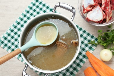 Photo of Delicious homemade bone broth and ingredients on white wooden table, flat lay