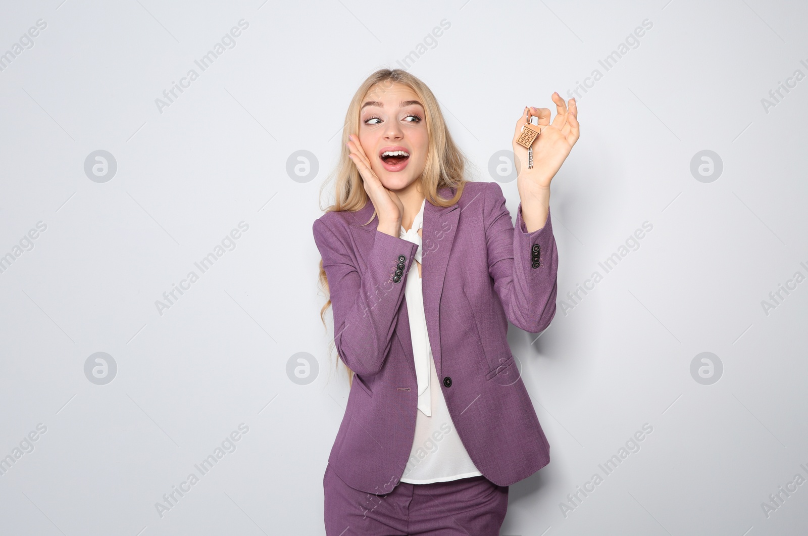 Photo of Happy young businesswoman with house key on light background