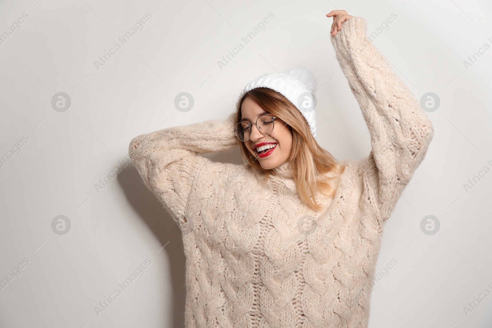 Photo of Beautiful young woman in warm sweater with hat on white background