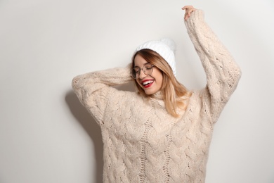 Beautiful young woman in warm sweater with hat on white background