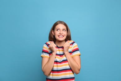 Portrait of emotional young woman on light blue background