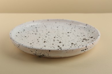 Photo of Beautiful ceramic plate on pale yellow table, closeup