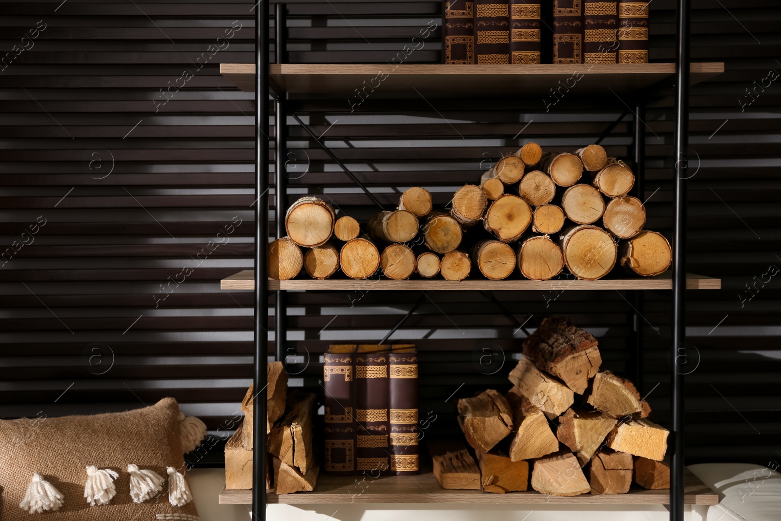 Photo of Shelving unit with stacked firewood and books near wall in room. Idea for interior design