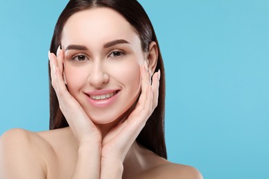 Portrait of beautiful young woman on light blue background. Space for text