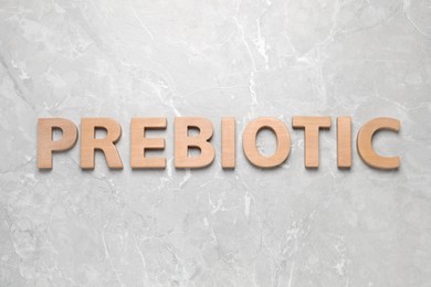 Word Prebiotic made of wooden letters on light grey marble table, flat lay