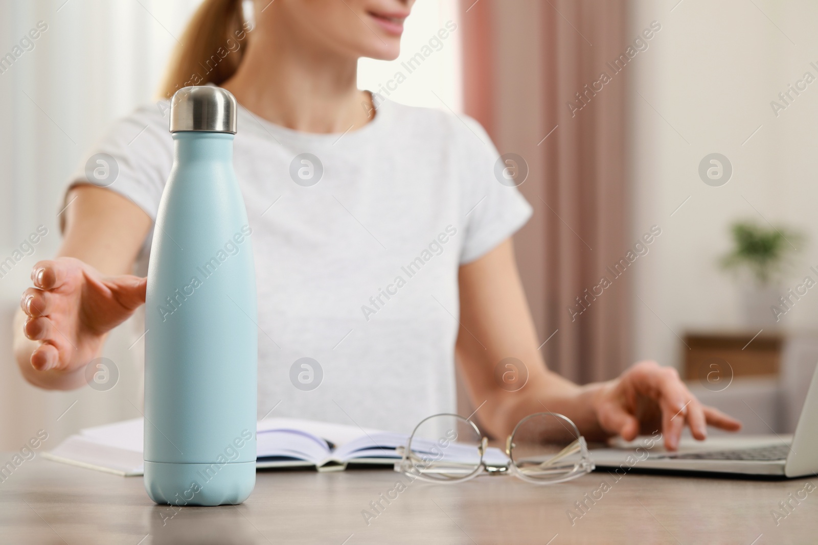 Photo of Woman taking thermo bottle indoors, closeup view