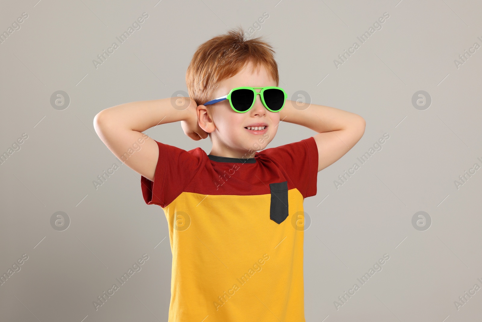 Photo of Cute little boy with sunglasses on light grey background